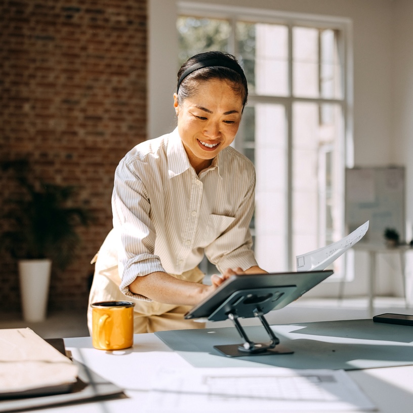 Casually clothed female architect using digital tablet while working at modern office