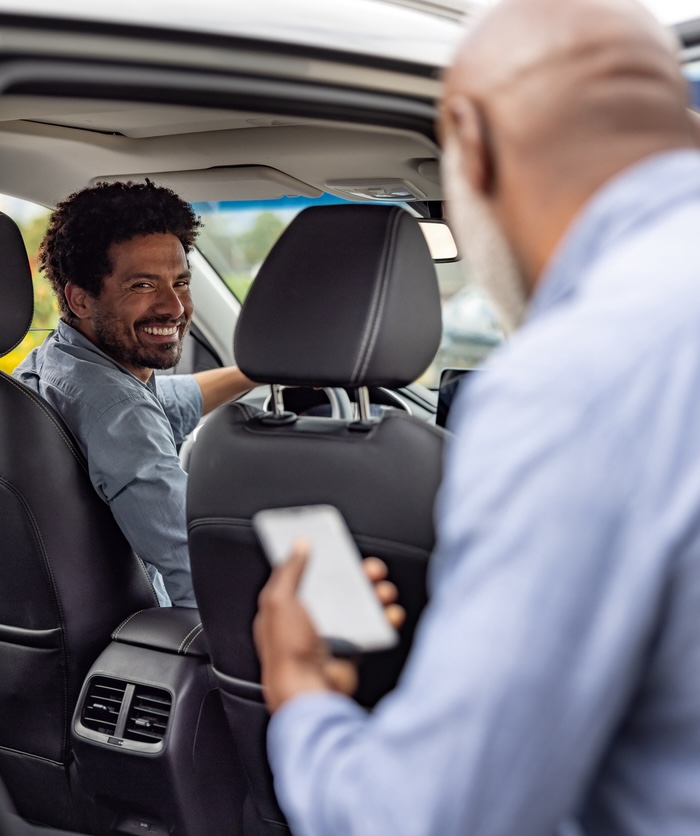 Driver picking up a passenger and smiling - mobility as a service concepts